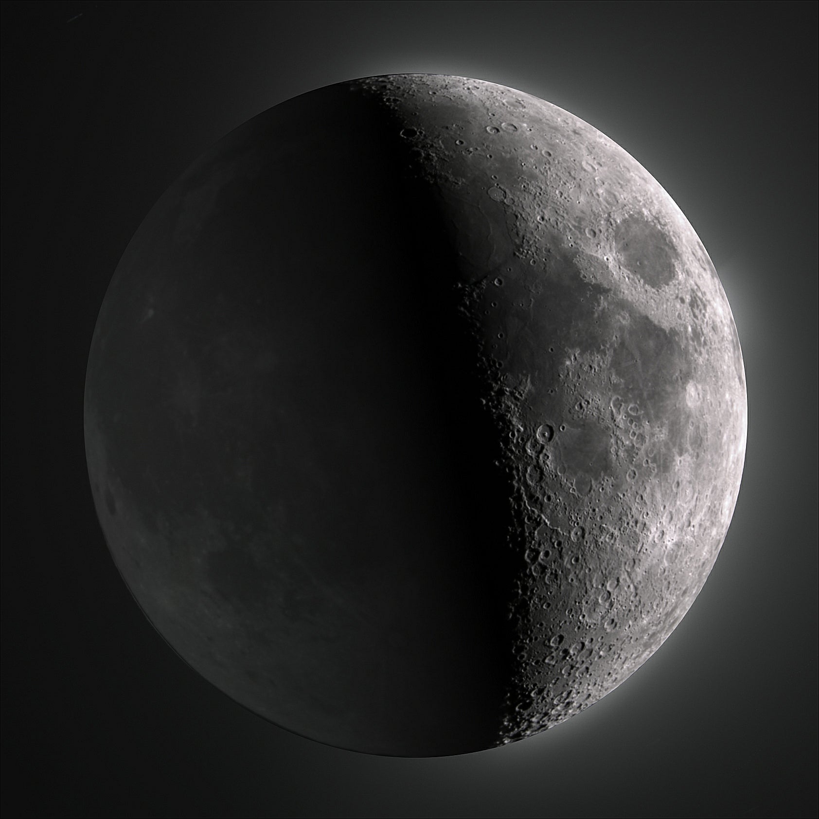 A grayscale close-up of the moon showing a half lit and half shadowed side against a dark background.