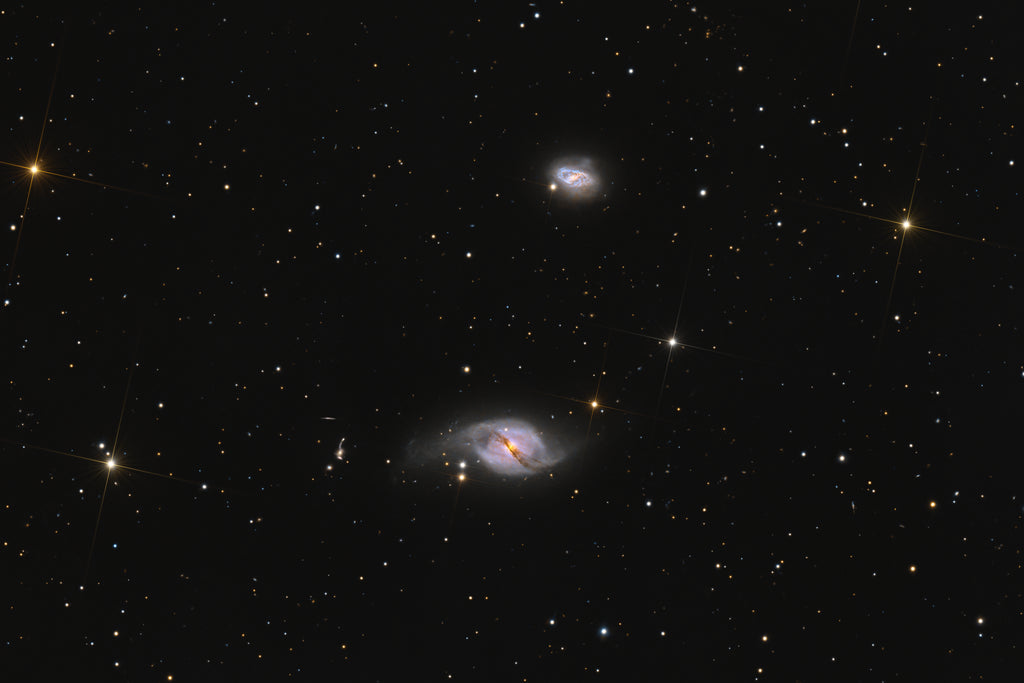 A deep-space astrophotography print featuring two spiral galaxies against a star-filled black sky with prominent star clusters.