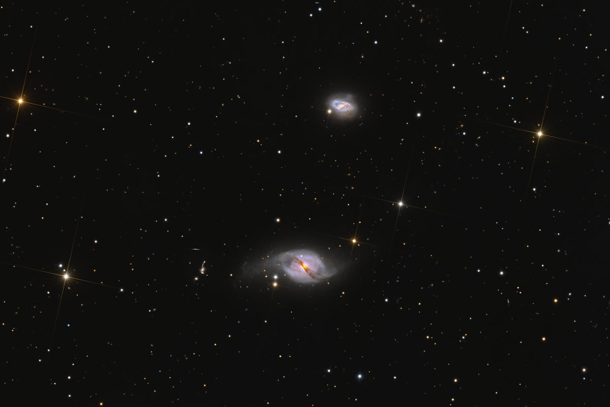 A deep-space astrophotography print featuring two spiral galaxies against a star-filled black sky with prominent star clusters.